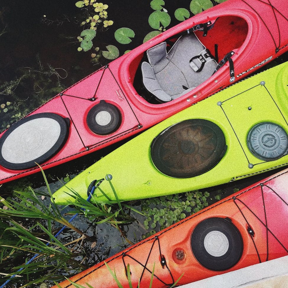 Three paddleboards: one pink, one neon yellow-green, one a gradient of orange and pink.